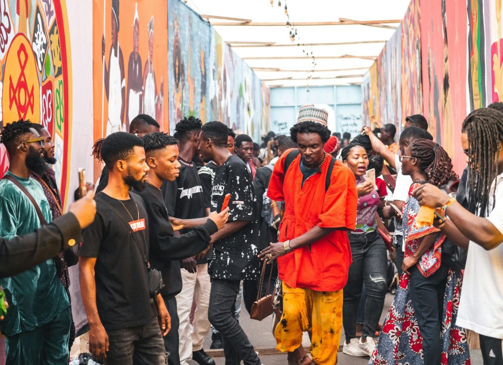 Dynamic crowd at an Accra festival, showcasing colorful murals and lively interactions.